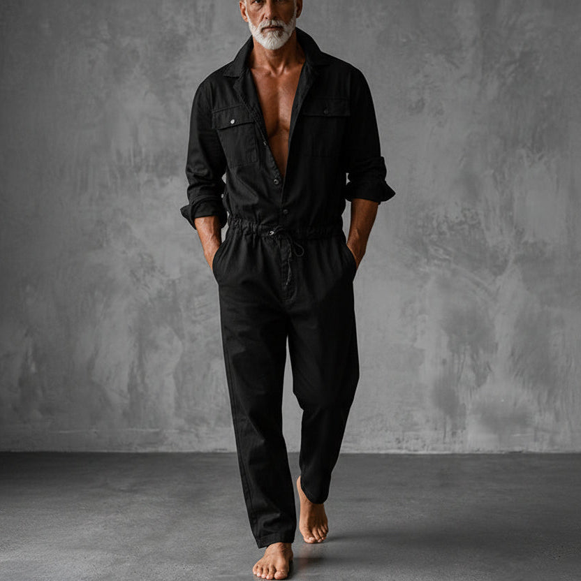 Der Overall in Schwarz an einem barfuß gehenden Model, mit Brusttaschen, Druckknöpfen und gerafftem Bund mit Kordel. 3