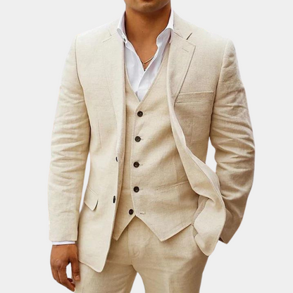 Dreiteiler in Cremebeige, getragen von einem Model mit weißem Hemd, Hand in der Hosentasche. 1