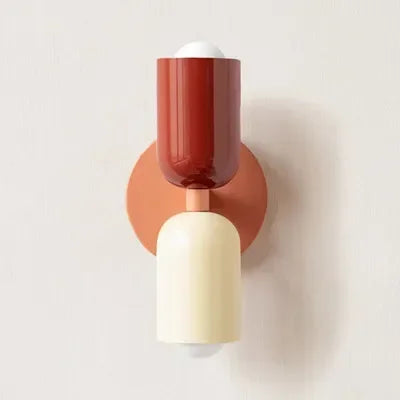 Einzelne Wandleuchte mit rotem oberem Schirm, cremefarbenem unterem Schirm und orangerosa Wandplatte vor heller Wand. 17
