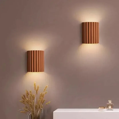 Zwei terrakottafarbene gerillte Wandleuchten leuchten an einer Wand über einem Sideboard mit Trockenblumen 8