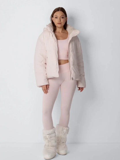 Ganzkörper-Frontansicht der rosa Steppjacke, offen getragen mit hohem Kragen über rosa Sportoutfit 10