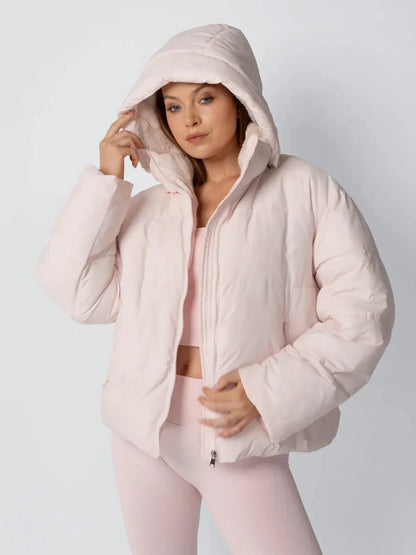 Model in der rosa Steppjacke mit übergezogener Kapuze, die Hand am Kapuzenrand 6
