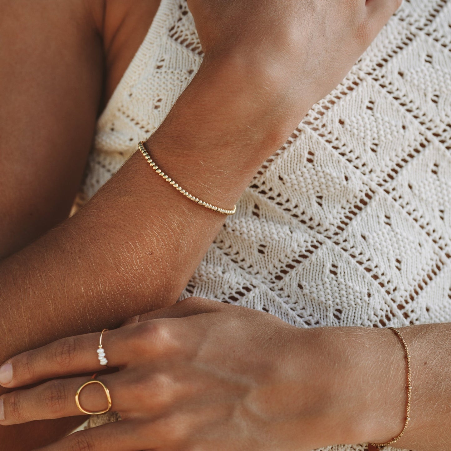 Goldene wasserdichte Armbänder auf gestricktem weißen Hintergrund, modische Schmuckaccessoires.