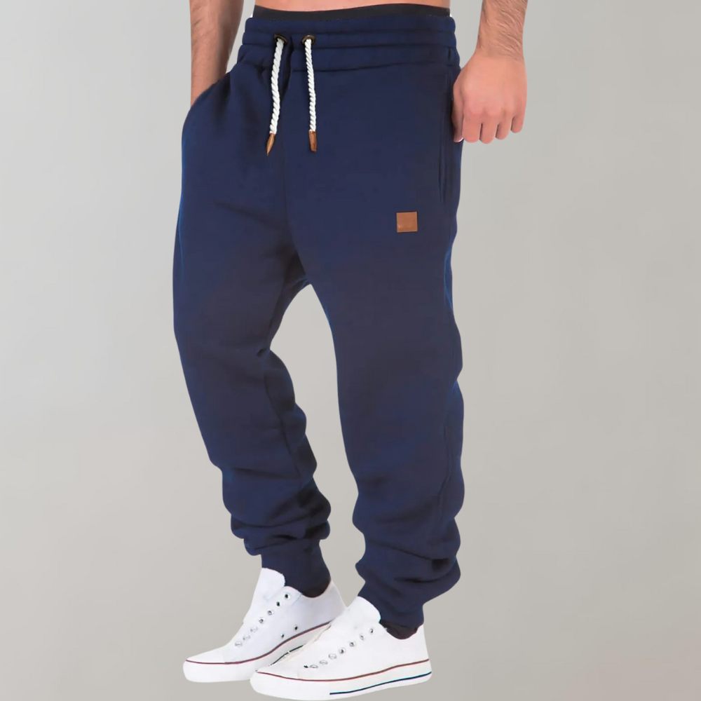 Marineblaue Jogginghose mit weißem Kordelzug, am Model getragen, leicht seitliche Ansicht mit weißen Sneakern 5