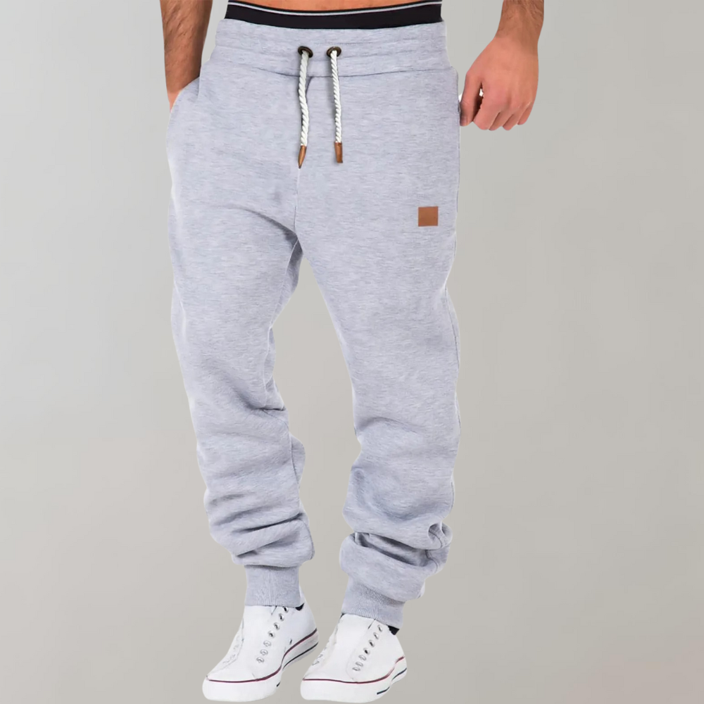 Hellgraue Jogginghose mit Kordelzug und Bündchen am Saum, getragen von einem Model in weißen Sneakern 4