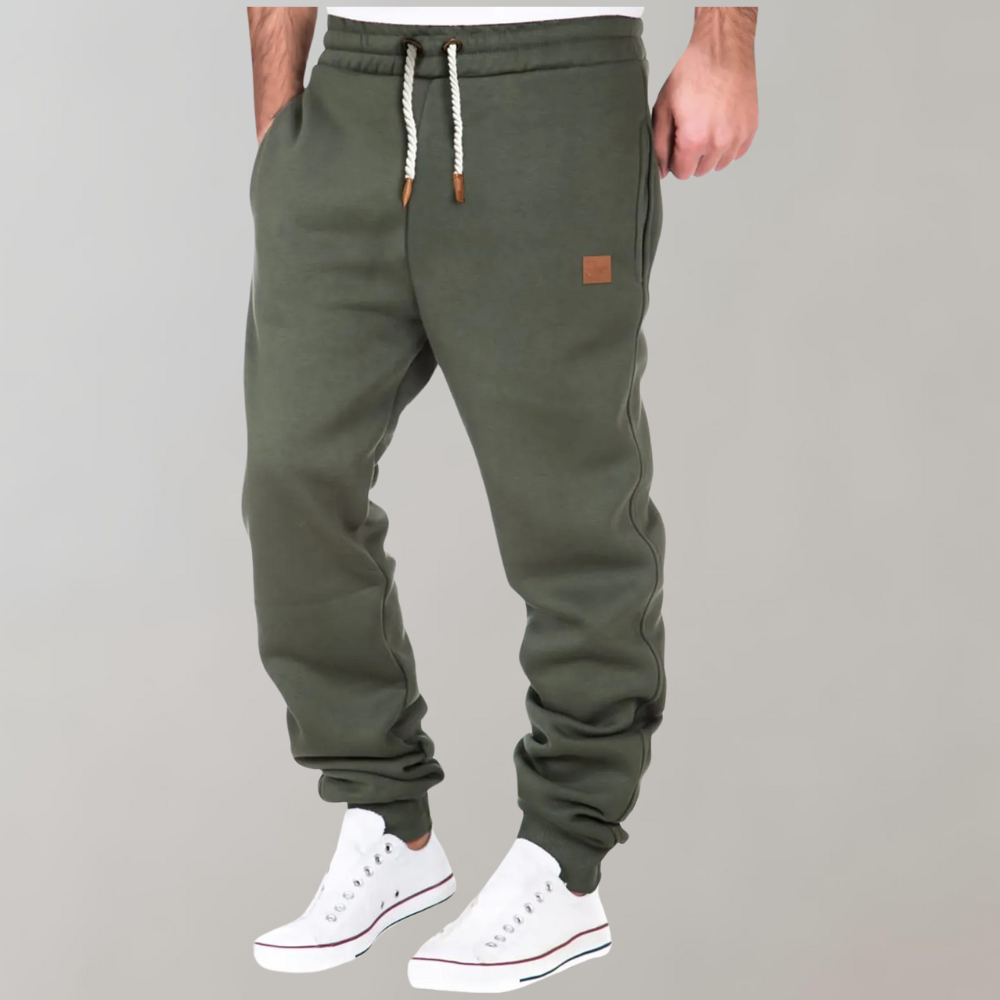 Olivgrüne Jogginghose mit Kordelzug, am Model getragen, leicht seitlich fotografiert, dazu weiße Sneaker 3