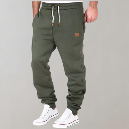 Olivgrüne Jogginghose mit Kordelzug, am Model getragen, leicht seitlich fotografiert, dazu weiße Sneaker 3
