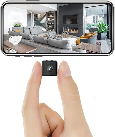 Winzige schwarze Würfelkamera zwischen Daumen und Zeigefinger, darüber ein Smartphone mit Live-Bild eines Wohnzimmers. 1