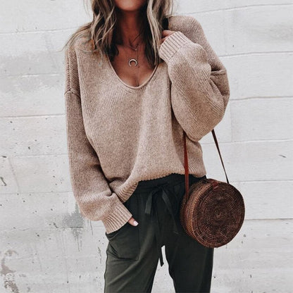 Frau in braunem V-Ausschnitt Strickpullover, lässig, mit runder Strohtasche, modisch.