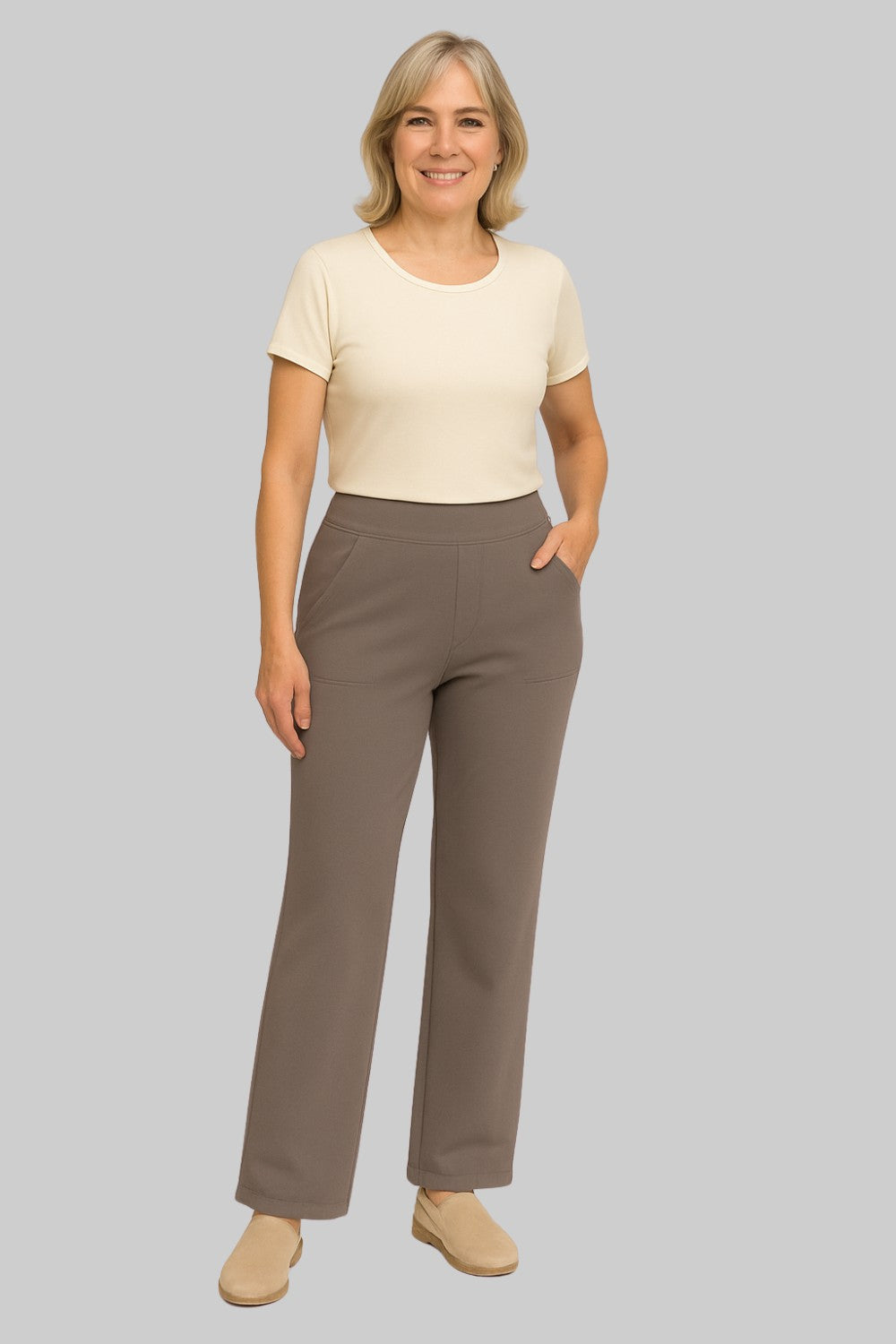 Frau in taupefarbener Hose mit hohem Bund und aufgesetzten Taschen, dazu ein cremefarbenes Kurzarmshirt und beige Slipper. 2