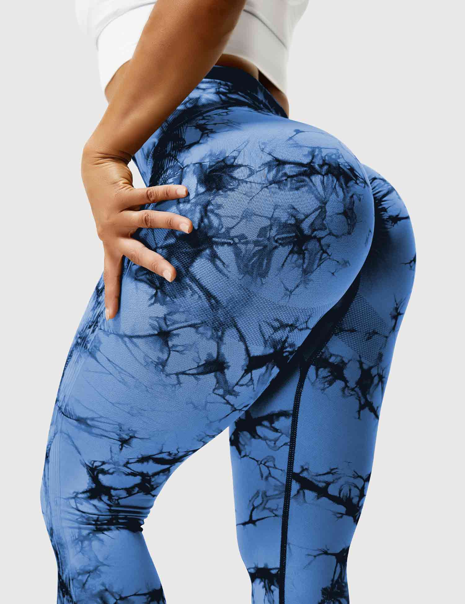 Frau in blauen, marmorierten Leggings, Sportbekleidung, Fitnessmode, elastisch, figurbetont.