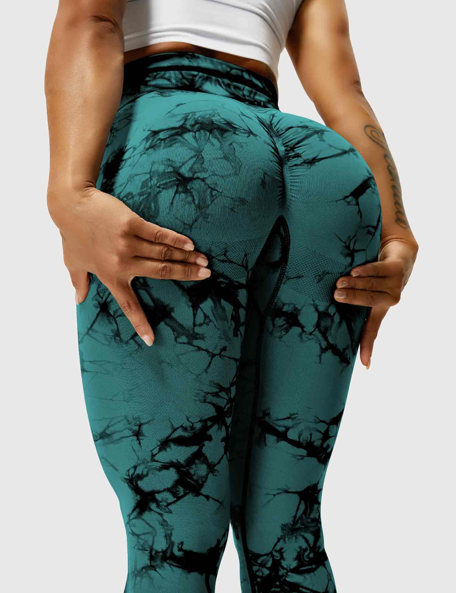 Frau in blaugrünen Leggings mit Marmormuster, Sportbekleidung, Fitnessmode, elastisch.