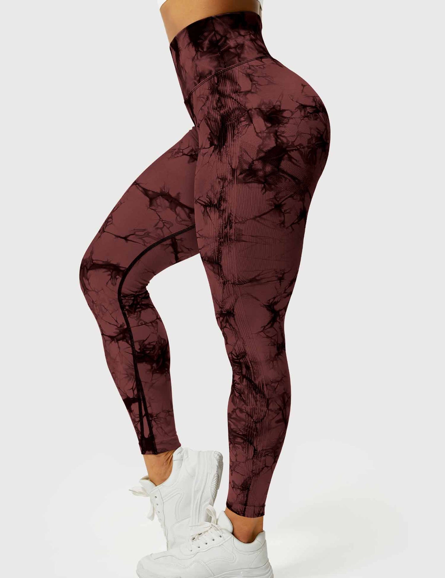 Frau in rotbraunen Leggings mit Marmormuster, hohe Taille, sportlich, weiße Turnschuhe.