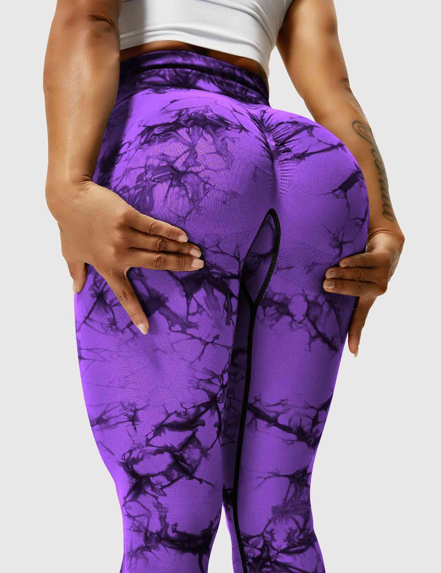 Frau in lila Batik-Leggings, Sportbekleidung, Fitnessmode, elastisch, bequem, trendig.
