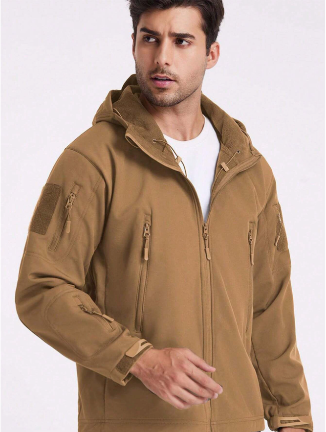 Mann trägt die beige Jacke offen über weißem T-Shirt; Fleecefutter an Kapuze und Kragen sowie Taschen sind sichtbar. 17