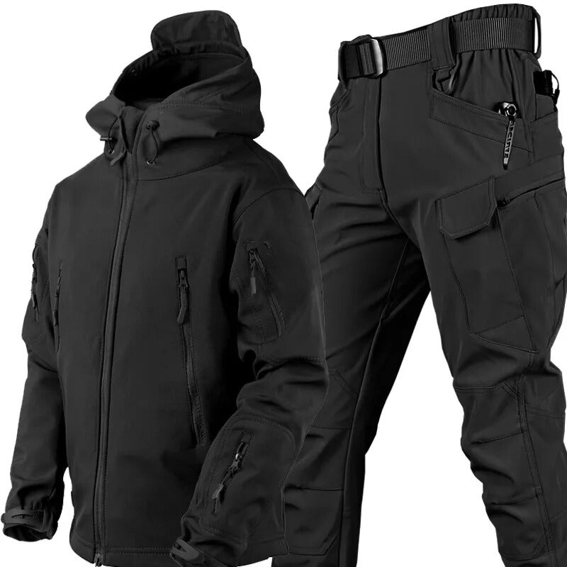 Schwarze Kapuzenjacke mit Reißverschlusstaschen am Ärmel und Brust neben der schwarzen Cargohose mit Gürtel und aufgesetzten Taschen, als Set in der Vorderansic 21